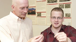 Grant Norton und ein Student schauen sich die neu entwickelten Batterien an.