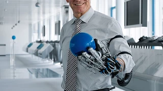 Wie gut die »ExoHand« die menschliche Hand dabei unterstützen kann, Gegenstände wie einen Ball zu halten, demonstriert hier der Festo-Vorstandsvorsitzende Dr. Eberhard Veit.