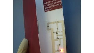Der erste Demonstrator eines auf eine Postkarte gedruckten Magnetsensors, integriert in einen Schaltkreis mit einer Leuchtdiode, die durch ein äußeres Magnetfeld angesteuert wird.