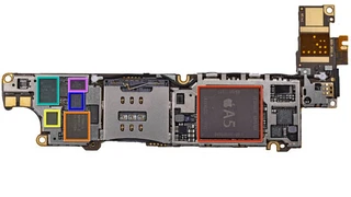 Die wichtigsten Chips des iPhone4S. Die Aufnahmen stammen von ifixit, dem Online-eparaturportal für elektronische Geräte. Ganz zentral befindet sich Apples A5-Prozessor, der von Samsung gefertigt wird. Orange eingefärbt ist Qualcomms RTR8605, ein Mul