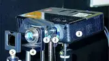 Bild 6: Der Laboraufbau des optischen Systems: Ein 3-D-Projektor (1) stellt die Bildquelle dar, das optische System vor dem Projektor besteht aus der Flüssiglinse (2), dem Okular (3), dem Fotoobjektiv (4) und einem optische Neutralglas-Filter (5) weg