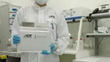 Eine Mitarbeiterin des KIT mit einem dort gefertigten Akku.