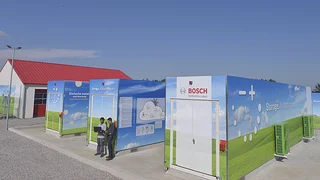 Bild 3. Gesamtansicht des Energiespeichers: In den Containern im Vordergrund sind die Lithium-Ionen-Akkuzellen untergebracht, das Gebäude im Hintergrund beherbergt die Vanadium-Redox-Flow-Batterien.