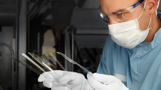 Schott fertigt ultradünne Gläser im sogenannten Down-Draw-Verfahren.  Dabei wird das Glas kontinuierlich aus der Schmelzwanne durch eine Düse  direkt nach unten zu einem Glasband gezogen. Dieses wird dann  für die weitere Verarbeitung auf Rollen gewi