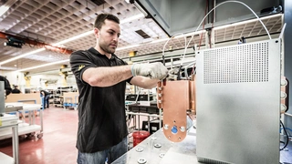 Das Bild zeigt einen Mitarbeiter am Prüfplatz, an dem die Powermodule einer Teilentladungsprüfung unterzogen werden. Diese Hochspannungsprüfung ist Bestandteil der Stückprüfung, die bei allen gefertigten Modulen durchgeführt wird.