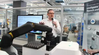 Im APAS-Showroom: Wolfgang Pomrehn, Produktmanager der APAS-Familie von Bosch, stellt die drei Modelle der Produktfamilie vor. Der Roboterarm »Assistant« stand bereits auf der Automatica 2016 im Mittelpunkt, daher wird auf der Vision die meiste Aufme