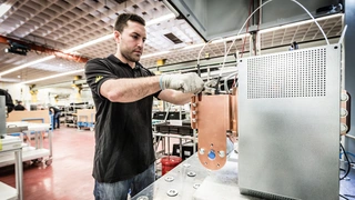 Das Bild zeigt einen Mitarbeiter am Prüfplatz, an dem die Powermodule einer Teilentladungsprüfung unterzogen werden. Diese Hochspannungsprüfung ist Bestandteil der Stückprüfung, die bei allen gefertigten Modulen durchgeführt