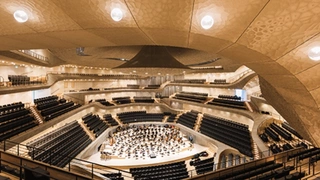 Rund 1200 mundgeblasene Glaskugelleuchten, die wie lichtgefüllte Wasserblasen aus der wellenförmigen Akustikdecke auftauchen stellen eine Hommage an die sturmerprobte Elbe gleich neben der Elbphilharmonie dar.