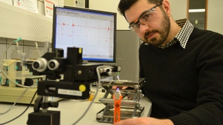 An einem Versuchsaufbau zur Kraftmessung testet Materialwissenschaftler Emre Kizilkan, wie stark das Kompositmaterial an Objekten haftet, wenn es mit UV-Licht bestrahlt wird.