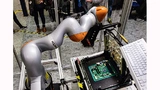 Bisher müssen Mainboards zum Testen manuell in einen Testadapter gelegt werden, Fujitsu experimentiert aber schon mit einem Roboter, der diese stupide Tätigkeit übernehmen kann