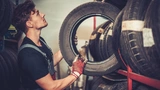 Ein Automechaniker in einer Reparaturwerkstatt wählt die richtigen Reifen für einen bestimmten Fahrzeugtyp aus.