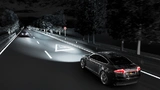 Fahrzeug mit blendfreiem Fernlicht und Warnhinweis auf der Straße