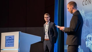 Moderator Samuel Sigfridsson (links) kündigt Julian Brand von Continental und seine Präsentation zum Thema „Dynamisches Fahrzeugnetzwerk-Management für zukünftige Ethernet-basierte Server-Architekturen“ an.