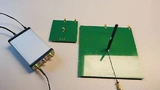 Für die Antennenmessungen dient der Vektor-NetzwerkAnalysator (VNA) von MegiQ (links), und zwei Testplatinen mit 95 mm × 95 mm Massefläche (Mitte) und 190 mm × 190 mm Massefläche (rechts). Die Antenne wird zur Messung vertikal auf der Testplatine mon