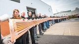 Die Mitarbeiter von Trackwise halten eine 26 m lange, mehrlagige, flexible Leiterplatte. Sie verteilt als Kabelbaum Energie und Signale über die Tragflächen eines unbemannten Flugzeugs