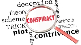 Lupe hebt das englische Wort conspiracy (Verschwörung) hervor