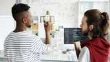Junge IT-Fachleute, die an einem transparenten Brett stehen und eine neue Software-Sprache analysieren