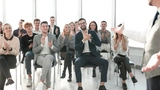 ein lächelnder Redner, der vor einem applaudierenden Publikum steht