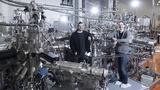 Dr. Peter Schüffelgen (l.) und Tobias Schmitt (r.) vor dem NanoCluster am Forschungszentrum Jülich, wo Kern-Komponenten des Hybrid-Qubits im Ultrahochvakuum gefertigt wurden.
